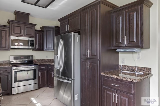 7136 Arroyo Blvd, Brownsville, TX 78526 - kitchen with appliances with stainless steel finishes, light tile patterned floors, dark stone countertops, and dark brown cabinets
