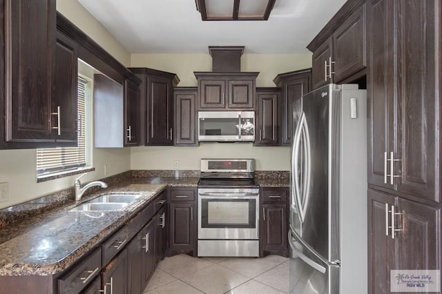 7136 Arroyo Blvd, Brownsville, TX 78526 - kitchen with stainless steel appliances, a sink, light tile patterned floors, dark brown cabinets, and dark stone counters