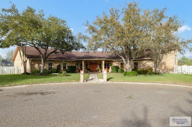 single story home with brick siding, fence, and a front lawn