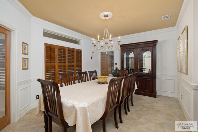 dining room featuring a notable chandelier, crown molding, and a decorative wall