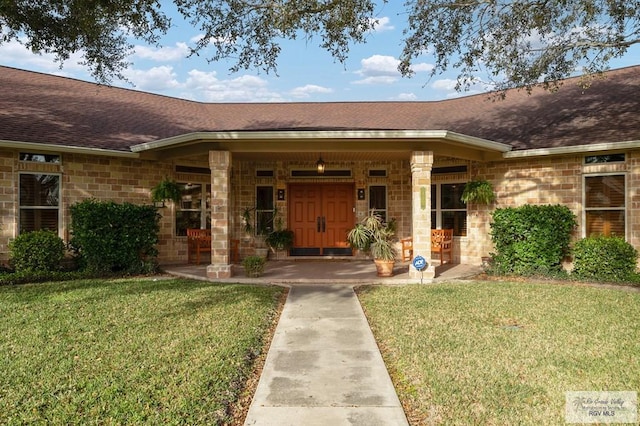 entrance to property with a yard, a porch, and roof with shingles