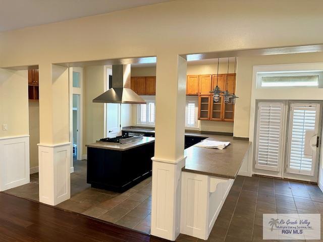 kitchen featuring ornate columns, dark hardwood / wood-style flooring, exhaust hood, and stainless steel gas stovetop