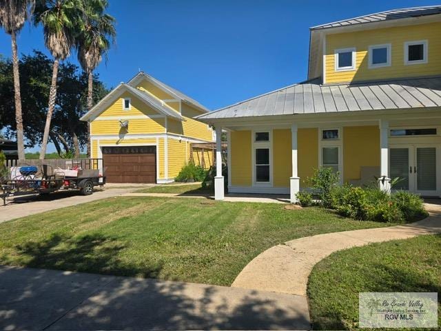 view of front of home featuring a garage, covered porch, and a front lawn