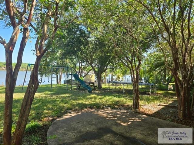 view of yard with a playground, a water view, and a trampoline