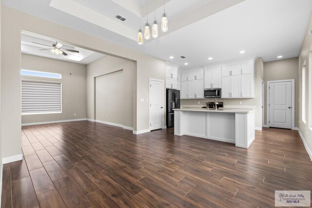 9372 Fan Palm Dr, Los Fresnos, TX 78521 - kitchen with stainless steel microwave, black refrigerator with ice dispenser, open floor plan, light countertops, and dark wood-type flooring