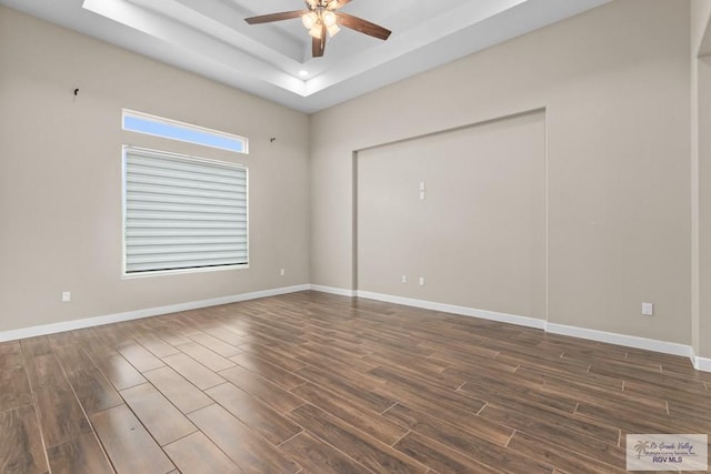 9372 Fan Palm Dr, Los Fresnos, TX 78521 - unfurnished room featuring ceiling fan, a tray ceiling, dark wood finished floors, and baseboards