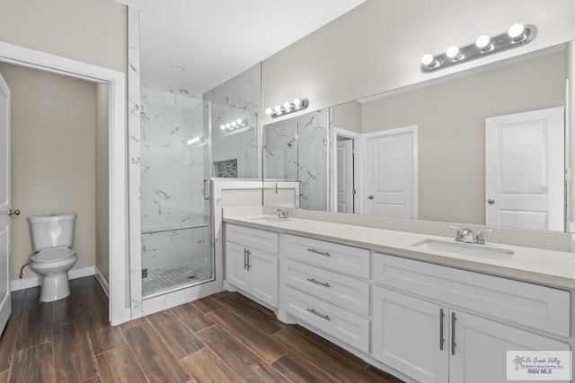 9372 Fan Palm Dr, Los Fresnos, TX 78521 - bathroom with a marble finish shower, toilet, wood finished floors, double vanity, and baseboards