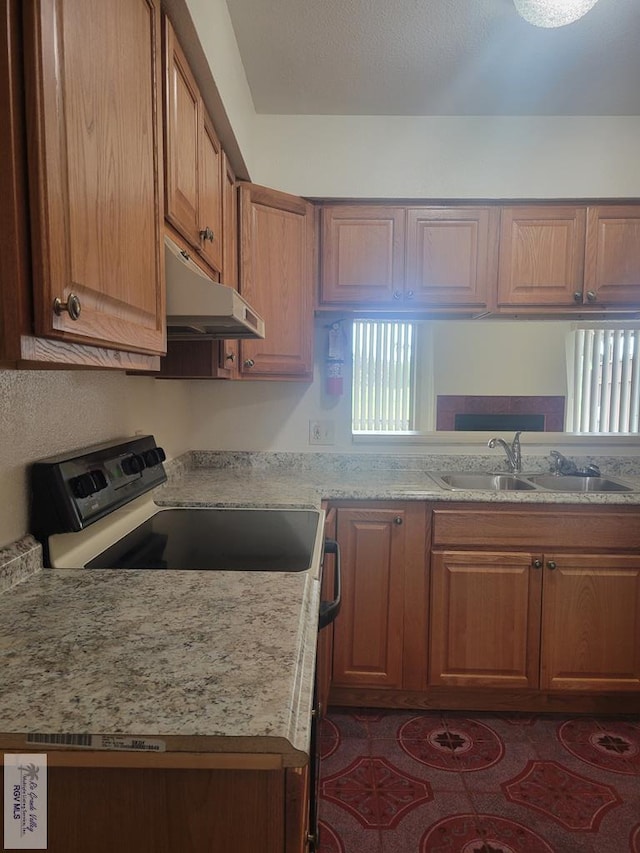 kitchen featuring light stone countertops, sink, and stainless steel stove