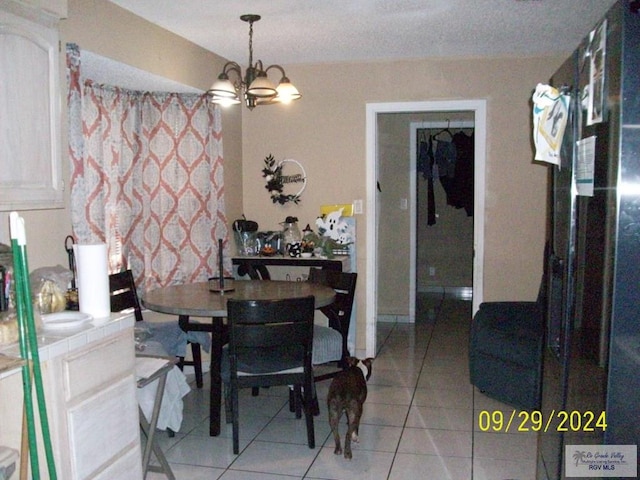 dining area featuring light tile patterned floors, a textured ceiling, and a notable chandelier