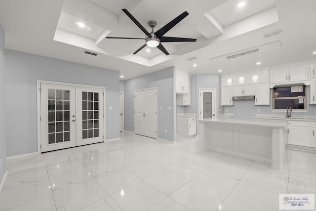 kitchen featuring visible vents, under cabinet range hood, french doors, white cabinetry, and a sink