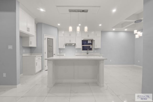 kitchen with a sink, light countertops, white cabinets, under cabinet range hood, and marble finish floor