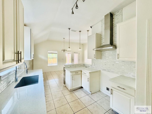 kitchen featuring sink, wall chimney exhaust hood, hanging light fixtures, decorative backsplash, and light tile patterned floors