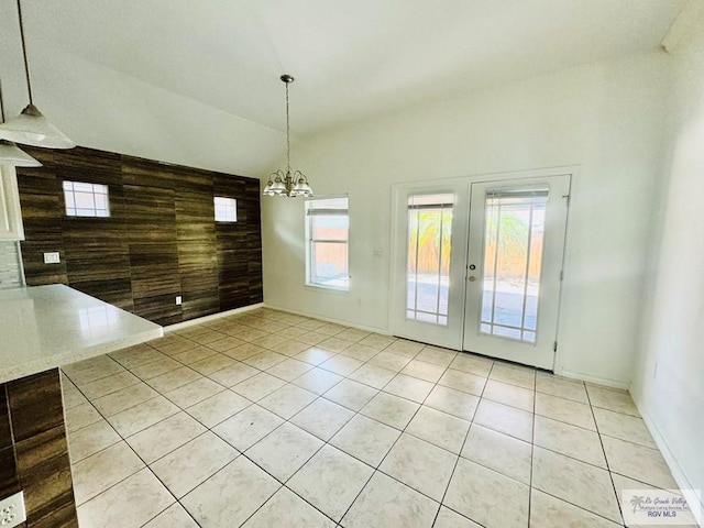 unfurnished dining area featuring light tile patterned floors, plenty of natural light, lofted ceiling, and a notable chandelier