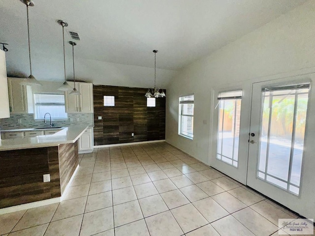 kitchen featuring decorative backsplash, sink, decorative light fixtures, lofted ceiling, and wood walls