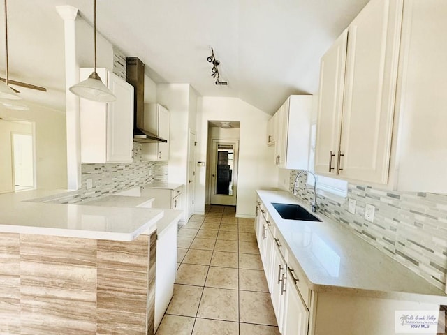 kitchen with kitchen peninsula, sink, white cabinets, and decorative light fixtures