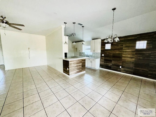 kitchen featuring hanging light fixtures, white cabinets, decorative backsplash, light tile patterned flooring, and ceiling fan with notable chandelier