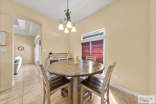 dining area featuring arched walkways, light tile patterned flooring, and baseboards