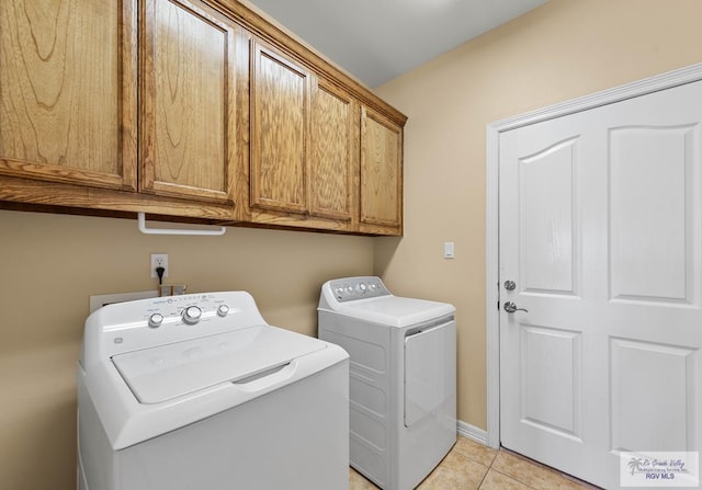 clothes washing area featuring baseboards, cabinet space, washing machine and clothes dryer, and light tile patterned flooring