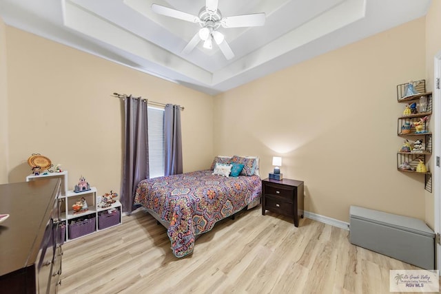 bedroom with ceiling fan, wood finished floors, a raised ceiling, and baseboards