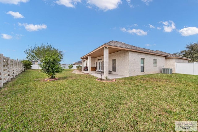 rear view of property with a patio, a fenced backyard, central AC, brick siding, and a yard