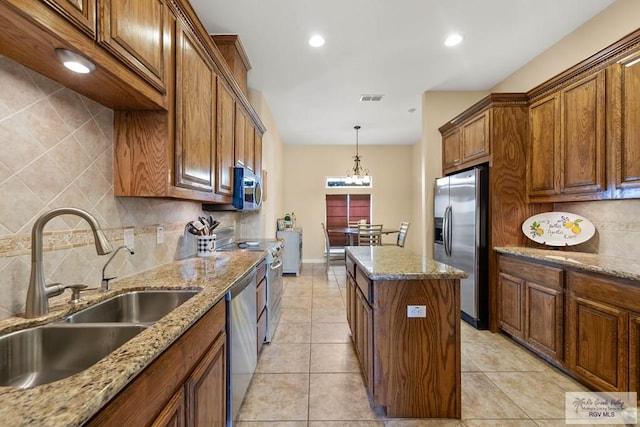 kitchen with a center island, brown cabinets, visible vents, appliances with stainless steel finishes, and a sink