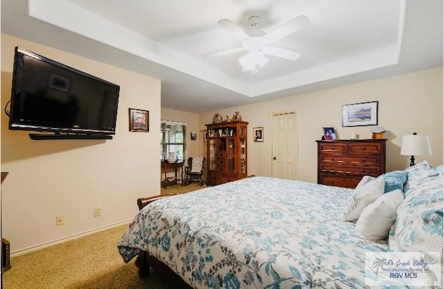 bedroom featuring ceiling fan, carpet, and a tray ceiling