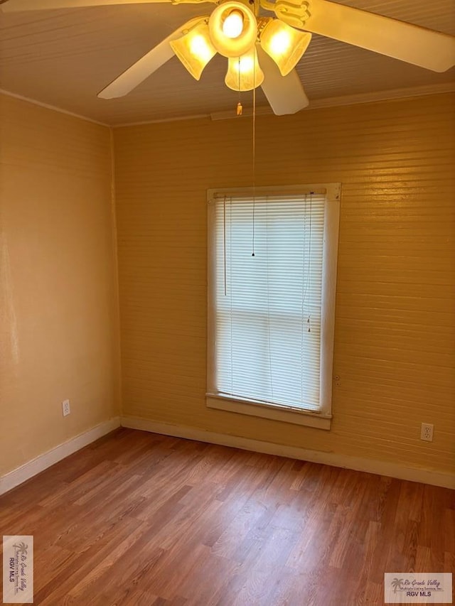 spare room with baseboards, ceiling fan, and wood finished floors