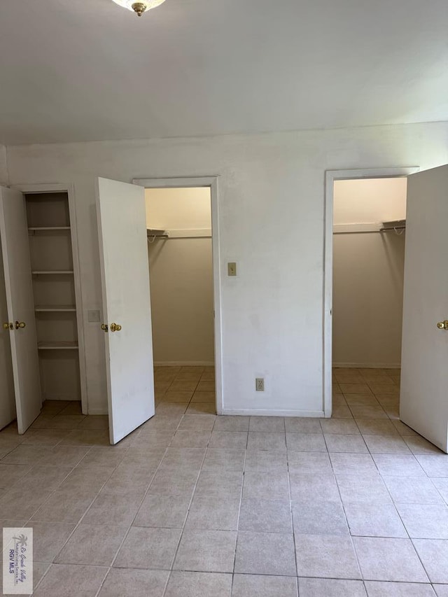 unfurnished bedroom with light tile patterned floors and a walk in closet