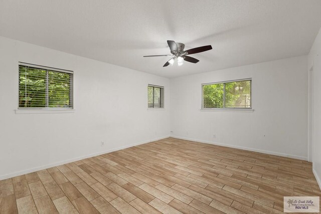 spare room with plenty of natural light, ceiling fan, and light wood-type flooring