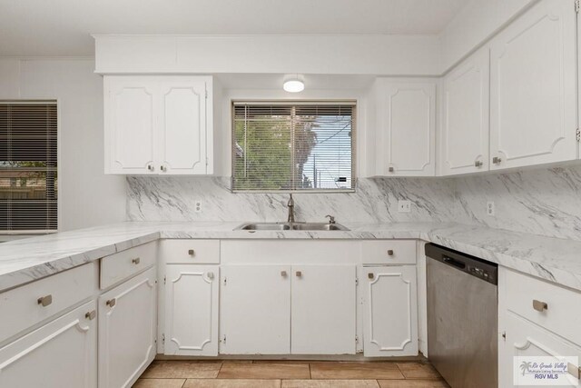 kitchen with tasteful backsplash, sink, white cabinets, and stainless steel dishwasher