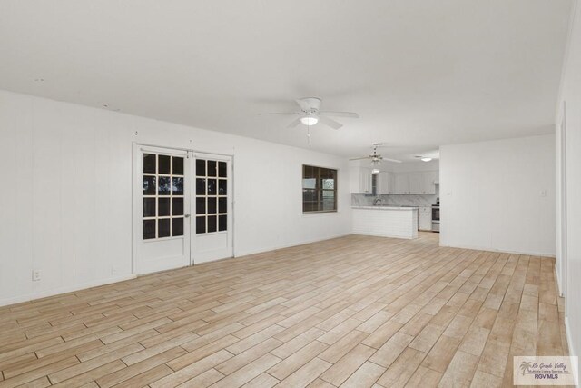 unfurnished living room featuring ceiling fan and light wood-type flooring