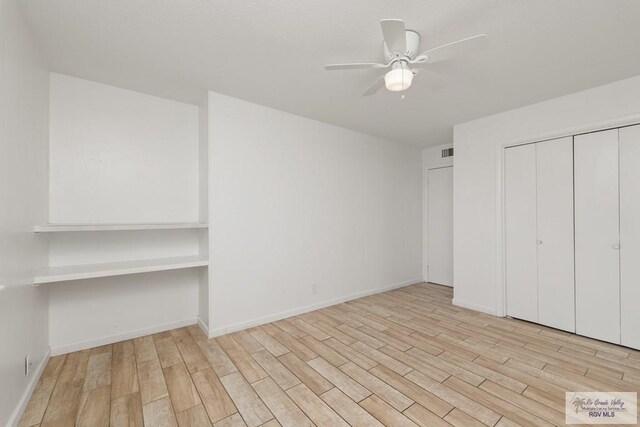 unfurnished bedroom featuring ceiling fan, light hardwood / wood-style floors, and built in desk