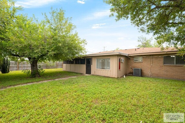 back of property featuring cooling unit and a yard