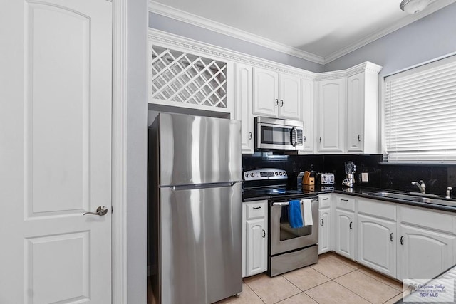 131 E Saturn Ln, South Padre Island, TX 78597 - kitchen featuring stainless steel appliances, dark countertops, white cabinetry, ornamental molding, and light tile patterned floors