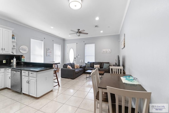 131 E Saturn Ln, South Padre Island, TX 78597 - kitchen with stainless steel dishwasher, dark countertops, ceiling fan, ornamental molding, and white cabinets