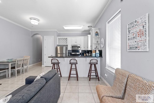 131 E Saturn Ln, South Padre Island, TX 78597 - kitchen featuring appliances with stainless steel finishes, light tile patterned flooring, ornamental molding, a kitchen breakfast bar, and a peninsula