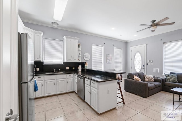 131 E Saturn Ln, South Padre Island, TX 78597 - kitchen featuring stainless steel appliances, a breakfast bar, a peninsula, dark countertops, and crown molding