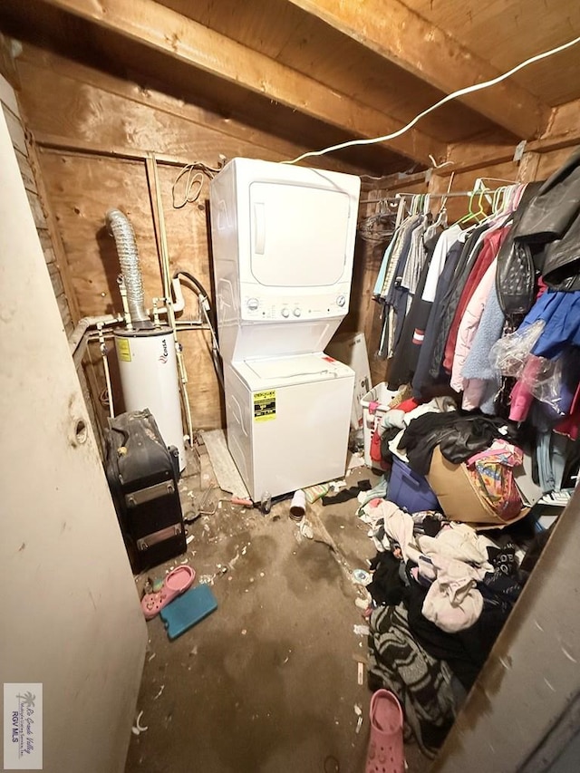 storage room featuring water heater and stacked washer and clothes dryer