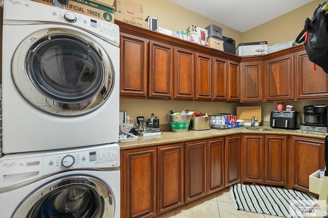 washroom featuring cabinets, light tile patterned floors, stacked washer / drying machine, and sink