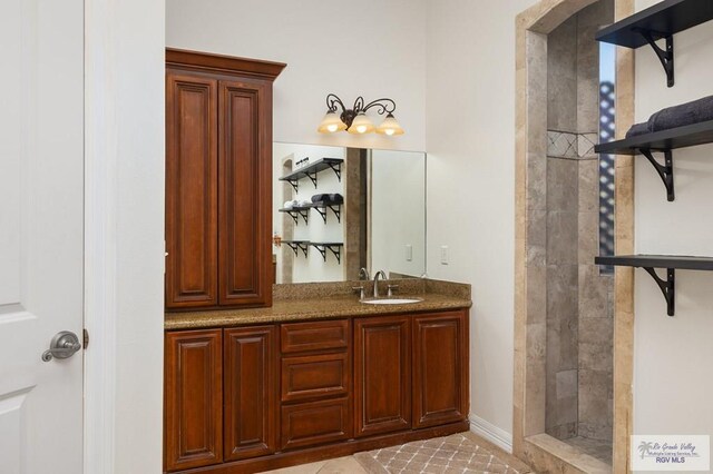 bathroom featuring a tile shower, tile patterned flooring, and vanity