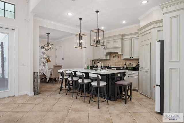 kitchen with hanging light fixtures, a kitchen breakfast bar, a kitchen island with sink, and crown molding