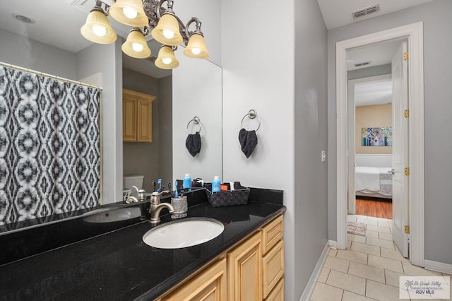 bathroom featuring a chandelier, vanity, toilet, and tile patterned flooring