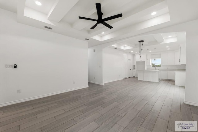 unfurnished living room featuring a tray ceiling and ceiling fan