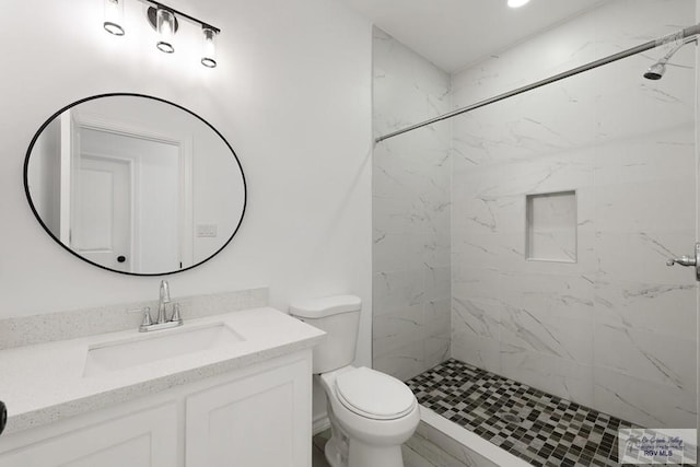 bathroom with vanity, toilet, and tiled shower