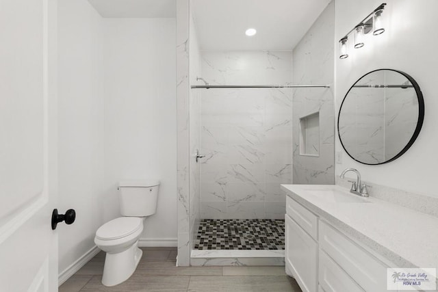 bathroom featuring tiled shower, vanity, and toilet