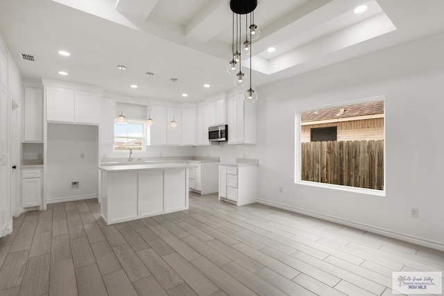 kitchen featuring a kitchen island, sink, white cabinetry, and hanging light fixtures