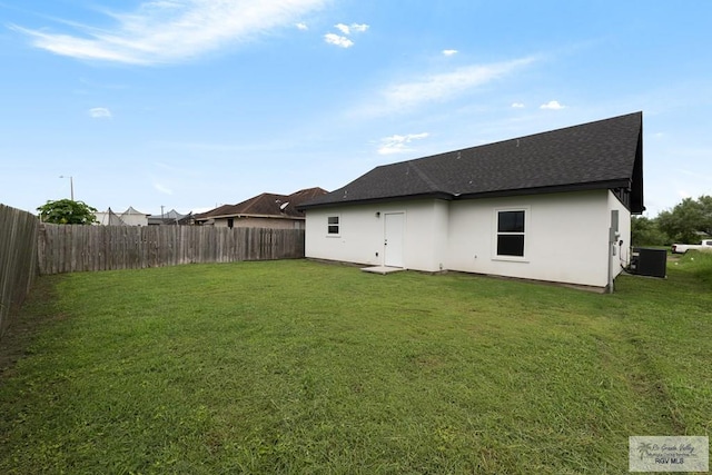 rear view of house with cooling unit and a yard