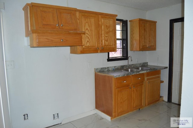 kitchen with marble finish floor, a sink, and brown cabinets