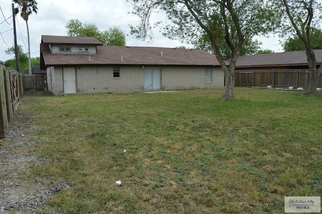 back of property featuring a lawn, brick siding, and a fenced backyard