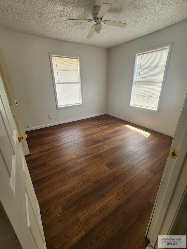 unfurnished room with dark wood-style floors, a ceiling fan, baseboards, and a textured ceiling